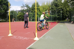 uczeń ćwiczący slalom na rowerze między pachołkami