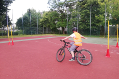 uczeń skręcający na rowerze między pachołkami